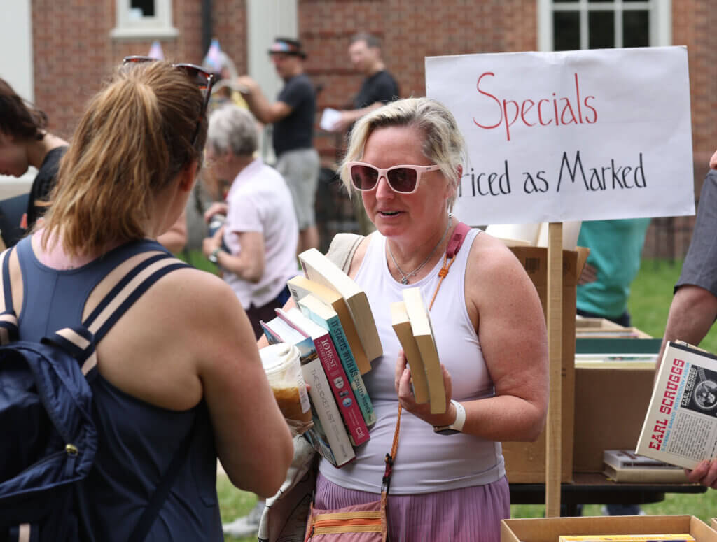 Amy Bell of Acton, right, loads up on reading material as she talks with friend Sarah Lynch, also of Acton.