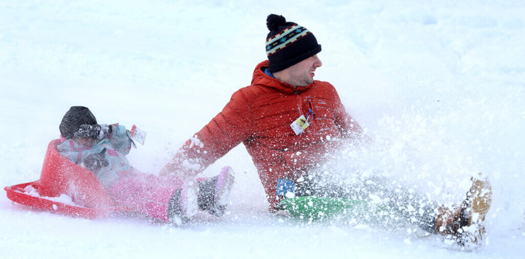 Vinny Tumminello of Acton and Willa, 2, kick up some powder. 
