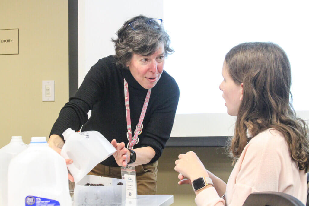 Library staffer Laura Mills talks to Adeline McNamara, right, about her milk jug terrarium. Photo: Dakota Antelman/The Acton Bridge