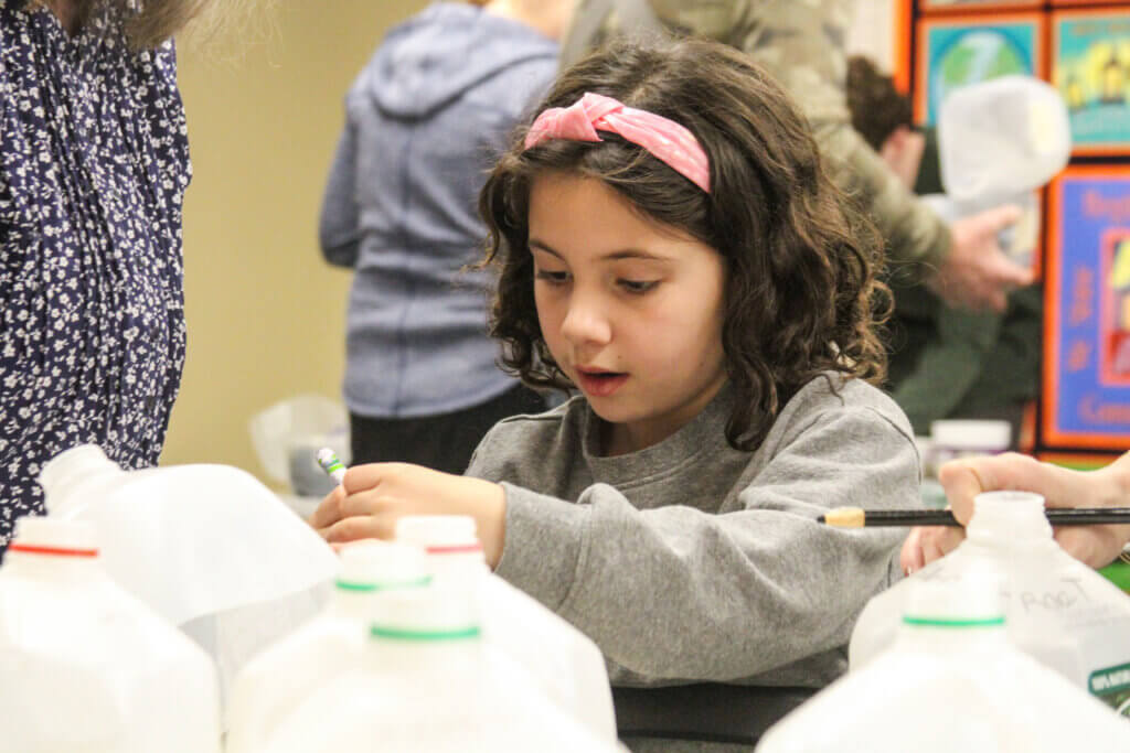 Lili Arslangul writes her name on a makeshift terrarium. Photo: Dakota Antelman/The Acton Bridge