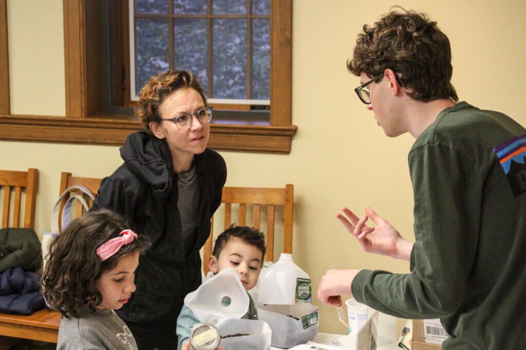 Gabrielle Besante speaks with event worker Reed Moffitt while her children browse the seeds. Photo: Dakota Antelman/The Acton Bridge