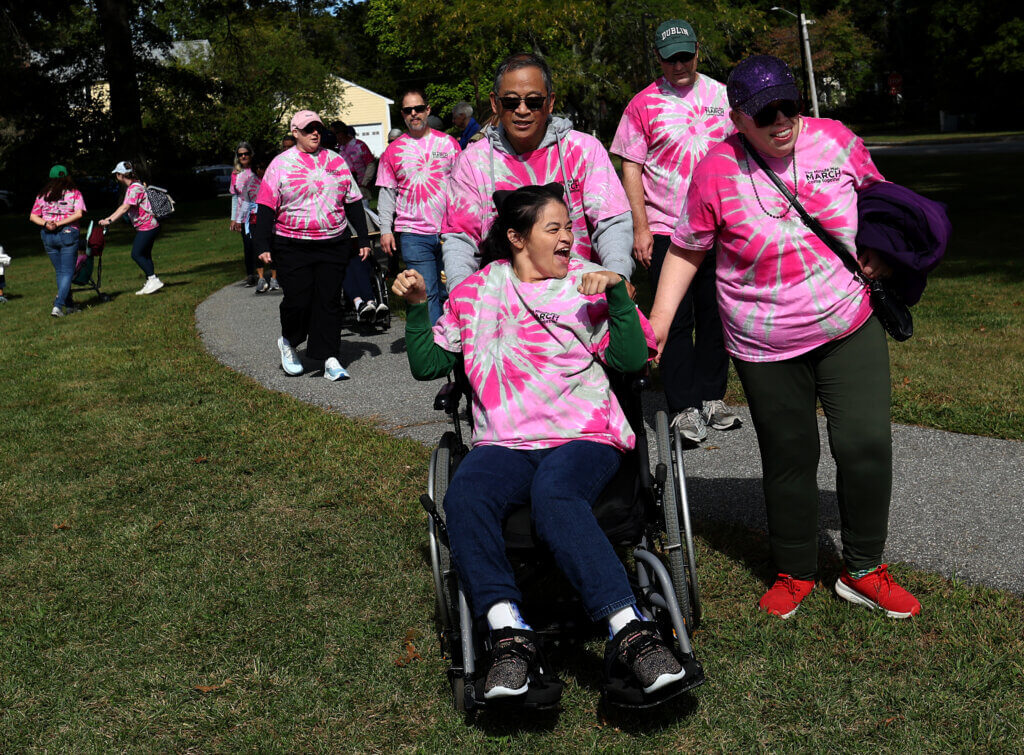 Ann Chang, center, celebrates as she and her father, Ray, and new friend Alisha Murphy reach the Alcott School finish line of Minute Man Arc’s 22nd annual one-mile Minute Man March on Saturday, September 19, 2026. The event raises funds and awareness the nonprofit’s programs supporting over 1,400 adults and children with disabilities in Middlesex County. Ken McGagh/The Acton Bridge