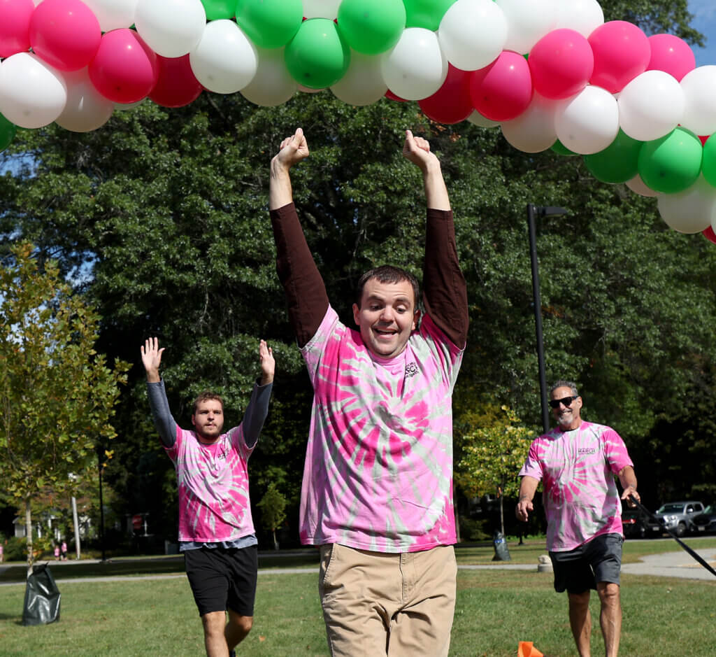 Framingham twins Frankie Saldi, front, and Bobby Saldi, left, 22, celebrate as they reach the finish lone of Minute Man Arc’s 22nd annual one-mile Minute Man March in Acton Center on Saturday, September 19, 2026. The event raises funds and awareness the nonprofit’s programs supporting over 1,400 adults and children with disabilities in Middlesex County. At right is the twins’ father, Frank Saldi. Ken McGagh/The Acton Bridge