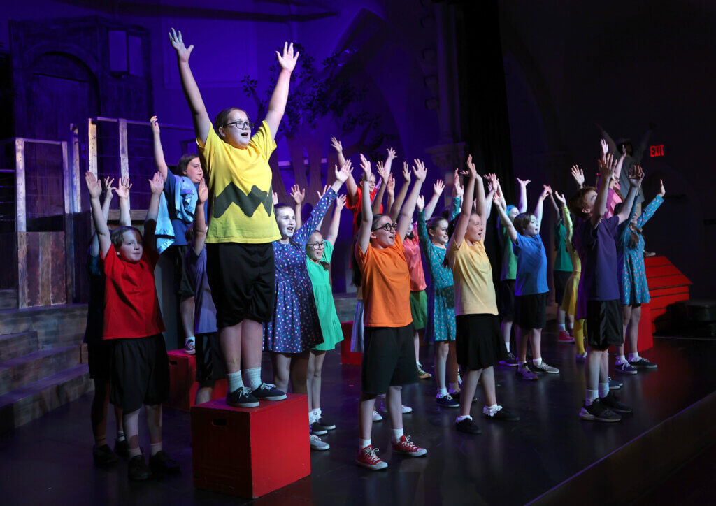 Stella DuBray as Charlie Brown, left, and cast conclude a number during the Acton Youth Theatre Summer Stock Troupe production of “You’re A Good Man Charlie Brown” on Thursday, July 23, 2026. The theater is celebrating its 50th anniversary, according to producer Lisa Evans. Ken McGagh/The Acton Bridge