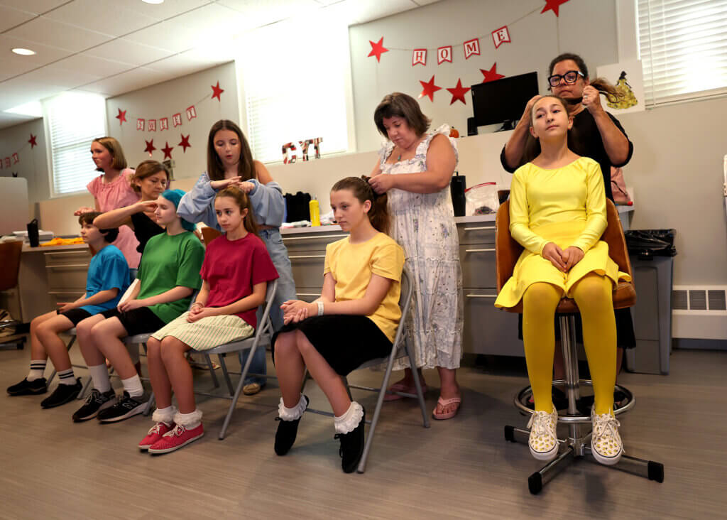 Emmy Saia, 13, of Acton, right, and other cast members get their hair done before the Acton Youth Theatre Summer Stock Troupe production of “You’re A Good Man Charlie Brown” on Thursday, July 23, 2026. Ken McGagh/The Acton Bridge