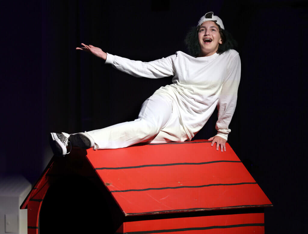 Snoopy (Abby Bairos) sings from atop the doghouse during the Acton Youth Theatre Summer Stock Troupe production of “You’re A Good Man Charlie Brown” on Thursday, July 23, 2026. Ken McGagh/The Acton Bridge