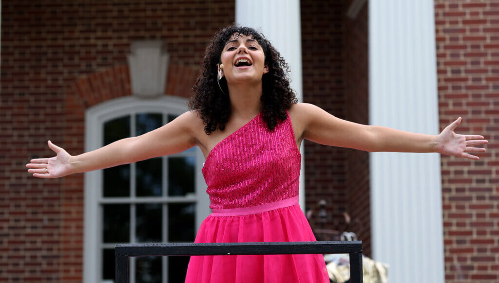 Eliza Zangerl, as Juliet, proclaims her love of Romeo from a balcony during the A World’s A Stage Players in association with the Acton Players presentation of “Romeo And Juliet” at the Acton Free Public Library lawn on Saturday, August 1, 2026. Acton Players presented William Shakespeare’s timeless tragedy with costumes and colors hailing from the 1980s. Ken McGagh/The Acton Bridge