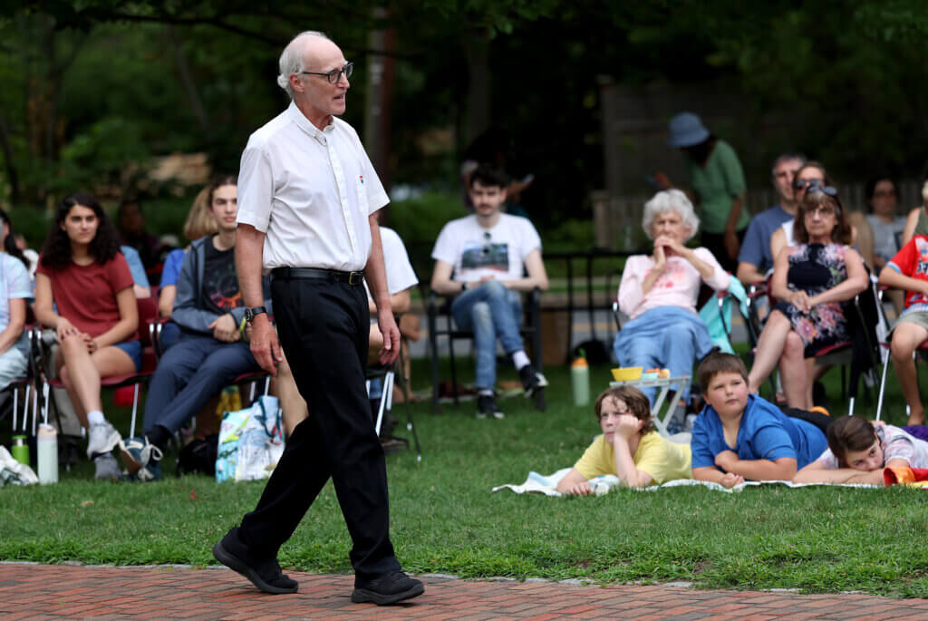 Ed Bernard, one of two cast members from Acton, strides through the Acton Free Public Libary lawn audience as Pastor Lawrence during the Acton Players presentation of “Romeo And Juliet” on Saturday, August 1, 2026. Ken McGagh/The Acton Bridge
