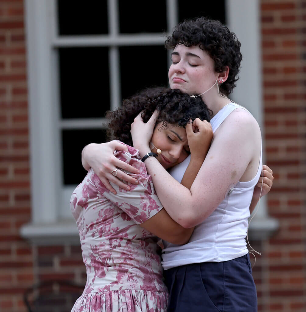 Romeo and Juliet, Sara Gluck, right, as Romeo, and Eliza Zangerl as Juliet, embrace during the Acton Players presentation of “Romeo And Juliet” at the Acton Free Public Library lawn on Saturday, August 1, 2026. Ken McGagh/The Acton Bridge