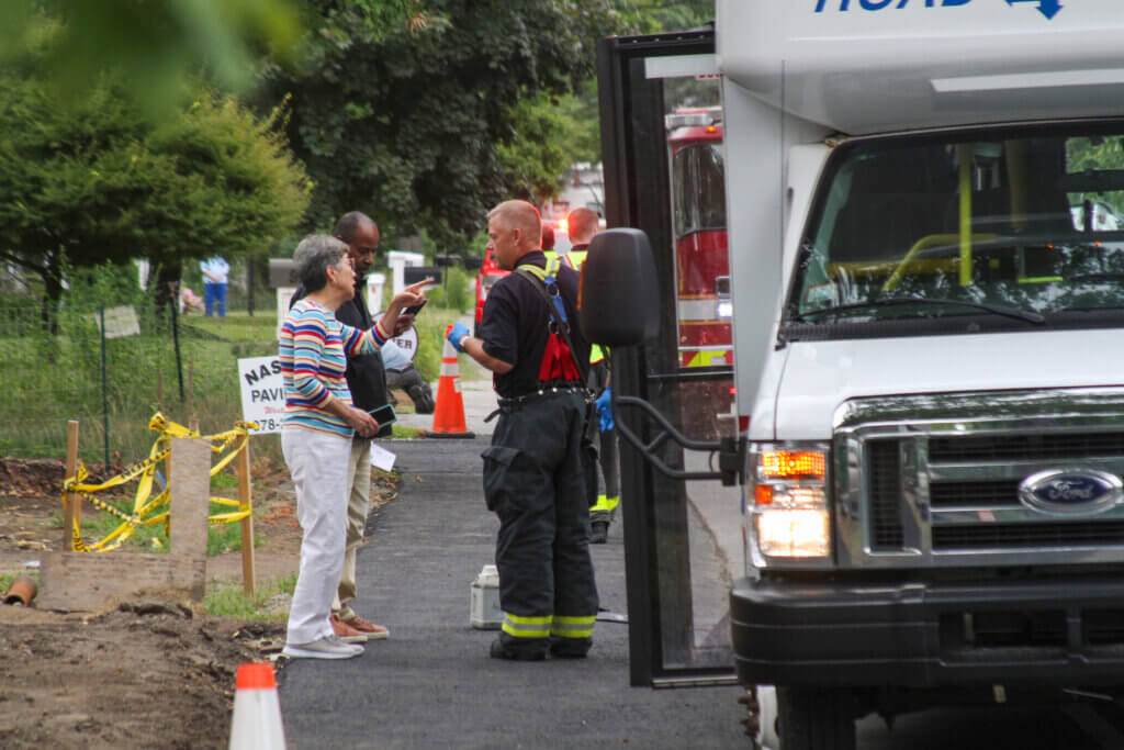Acton resident and bus passenger Kay Aoki, left, speaks with a firefighter. Photo: Dakota Antelman/The Acton Bridge