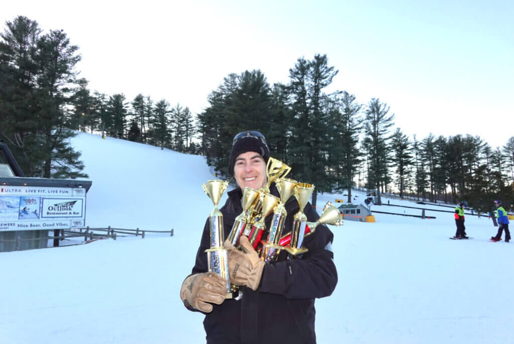 Coach Amy Brooks with the trophy haul from the Mass Bay West All League Race in February 2025. Photo by Maddie Clancy