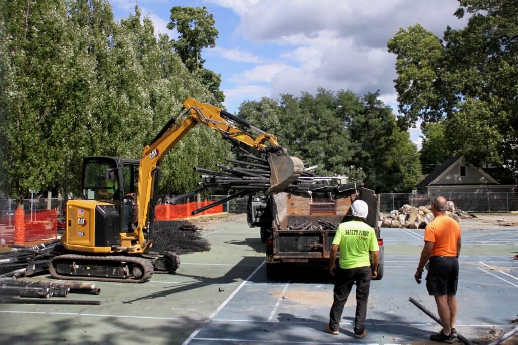 Workers watch while a colleague drops into a truck what’s left of the fencing that surrounded the Rideout pickleball and tennis courts. Photo: Dakota Antelman/The Acton Bridge