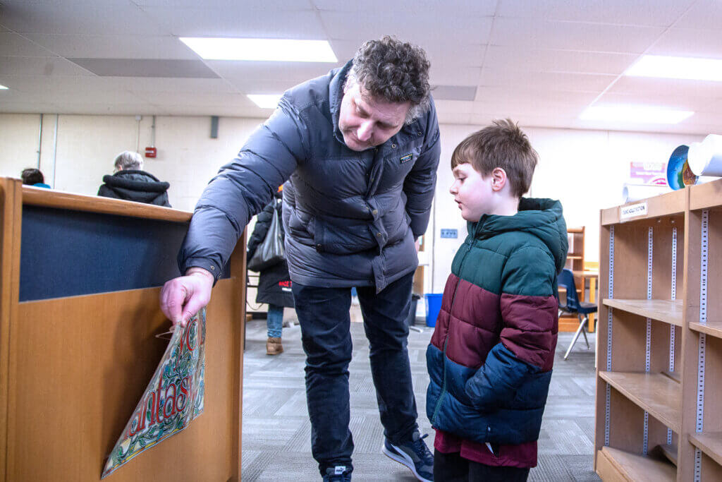 Scott Moore and his son look at a poster inside the library at the Sanborn school. Photo: Stephen Beyer/The Acton Bridge