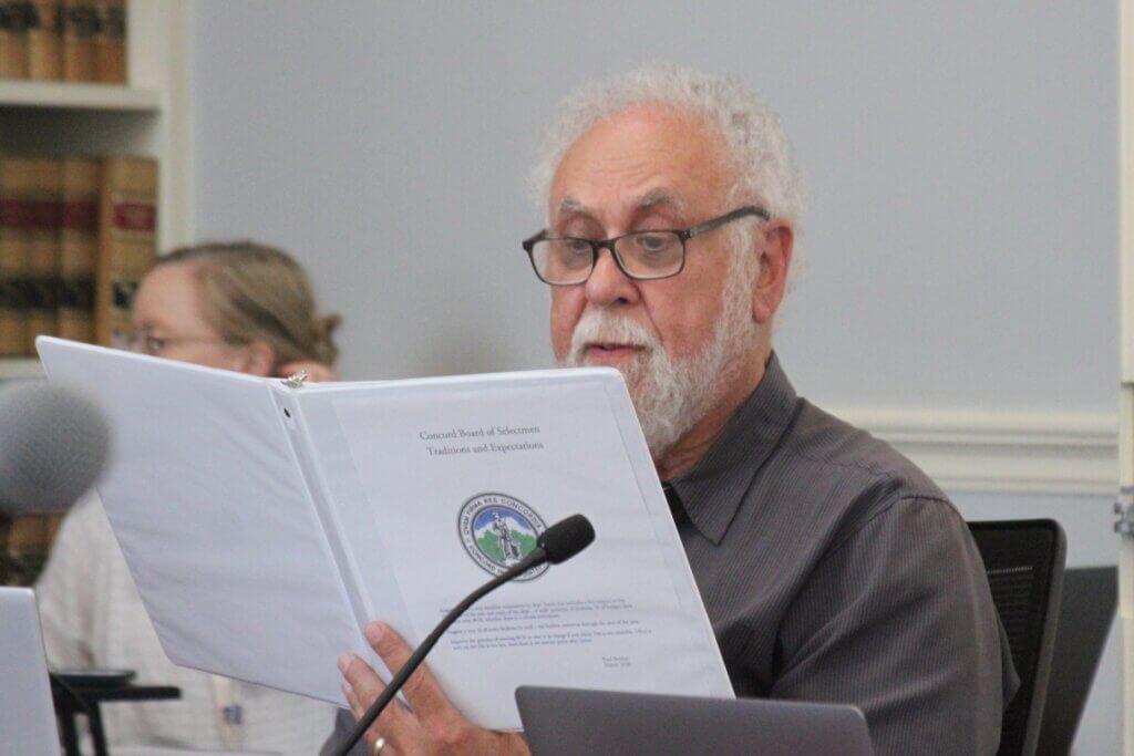 Select Board member Paul Boehm held up a Select Board “traditions and expectations” binder as he vied for the clerk’s job. Photo: Dakota Antelman/The Acton Bridge