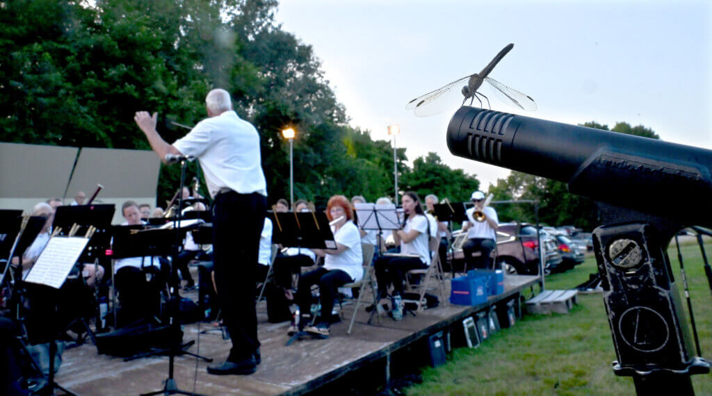 A dragonfly alights on a microphone as musical director Jim O’Dell conducts the Acton Band at Fruitlands Museum in Harvard, continuing a tradition that began 40 years ago. Photo: Ken McGagh/The Acton Bridge