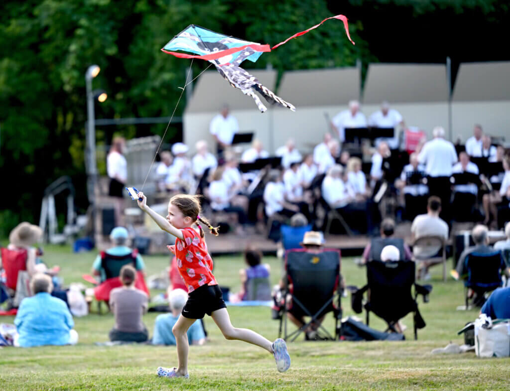 A youngster in the audience flies a kite as the Acton Band plays on. Photo: Ken McGagh/The Acton Bridge