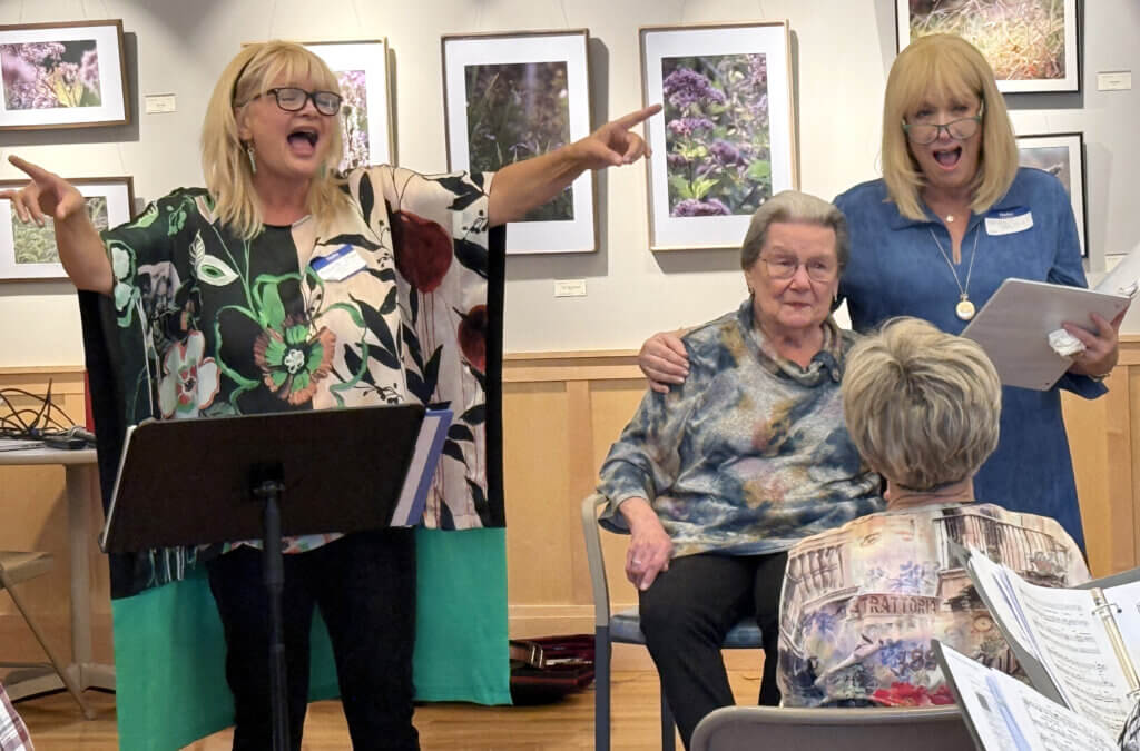 CCHS alumnae Michelle Oram, left, and Nancy Halpin, right, serenade Dorothy DiDomenico at an October 18 tribute to their retired teacher. Photo: Laurie O’Neill/The Acton Bridge