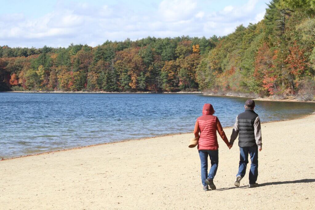 A couple enjoys a stroll at foliage-framed Walden Pond. Photo: Dakota Antelman/The Acton Bridge