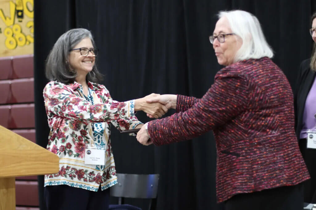 Outgoing 10-year Moderator Carmin Reiss presents successor Karlen Reed with the gavel, representing the formal transfer of the stewardship of Acton's centuries-old citizen legislature. Photo: Trace Salzbrenner/The Acton Bridge