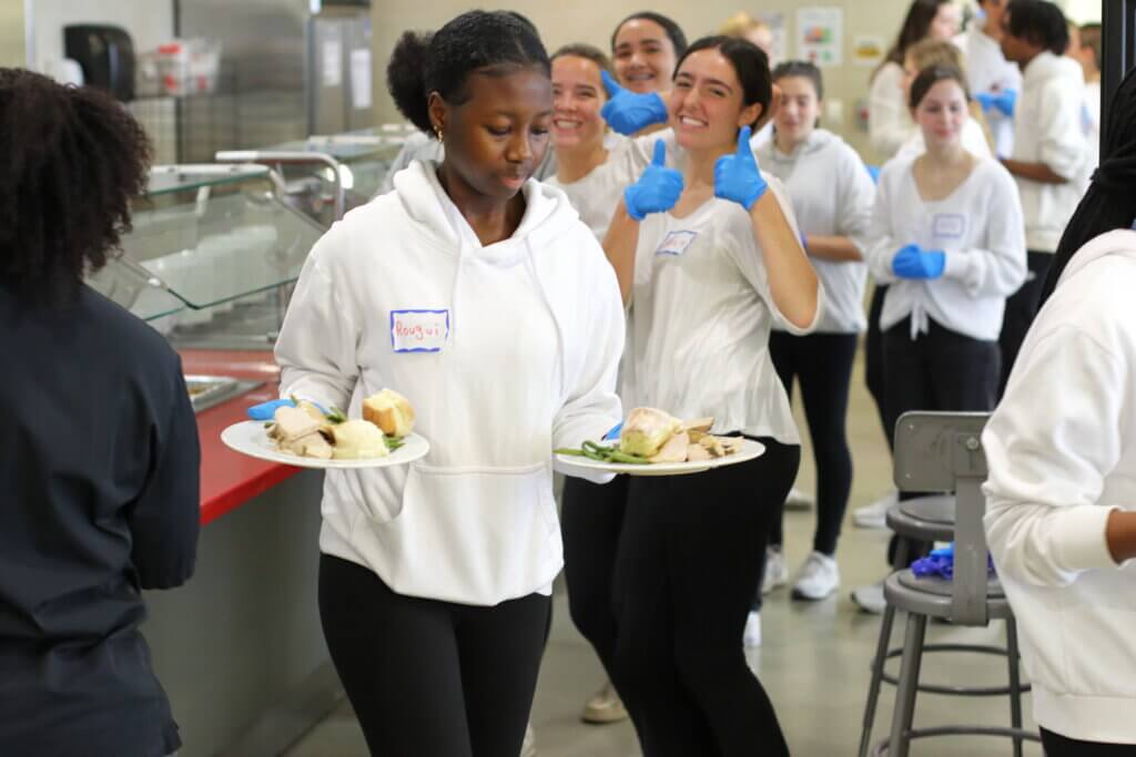 Acton-Carlisle High School student Rougui Bangoura grabs prepped meals to shuttle to tables. Photo: Trace Salzbrenner/ The Acton Bridge