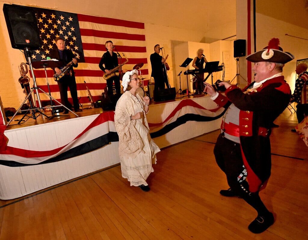 Peter Secor, captain of the Bedford Minutemen, dances with Linda Costigan Williamson of Weston as the band the Love Dogs plays during the 2025 Patriots’ Ball at the Acton Armory on Saturday, April 12, 2025. Ken McGagh/The Acton Bridge
