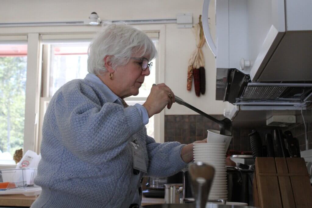 Event volunteer Amanda Mujica serves apple cider warmed on an induction cooktop during a January Mid-Winter Home Tour event at Geoff and Electa Tritsch’s home on Heaths Bridge Road. Photo: Dakota Antelman/The Acton Bridge