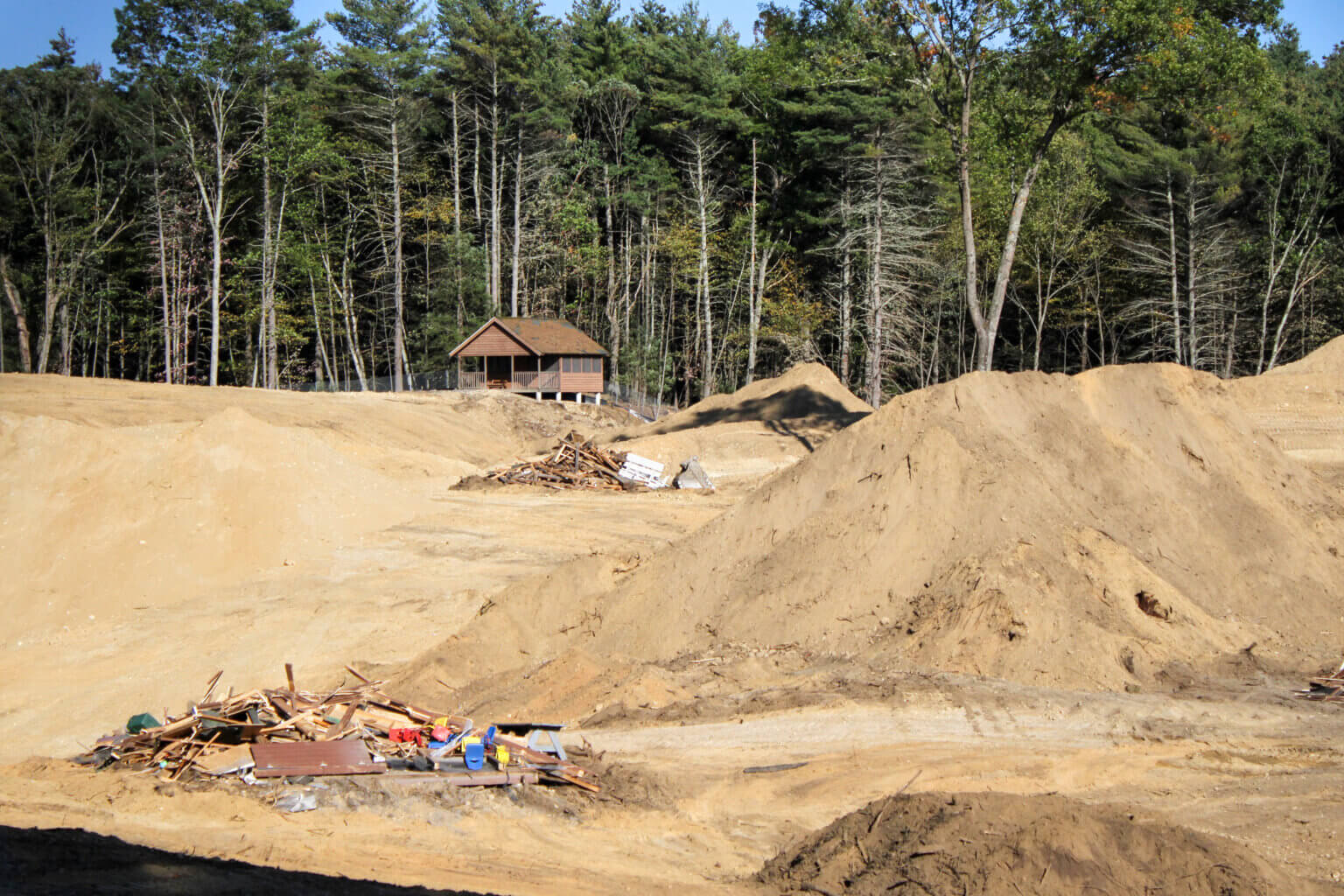 A since-demolished camp cabin overlooked a field of dirt and rubble this month as crews started site work for the planned Alta Thoreau apartments. Photo: Dakota Antelman/The Acton Bridge