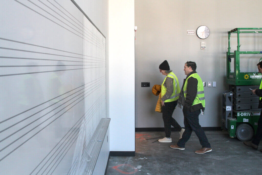 Acton-Carlisle School Committee members Julie Viola and Brian Waterson walk past a blank whiteboard in a finished classroom.