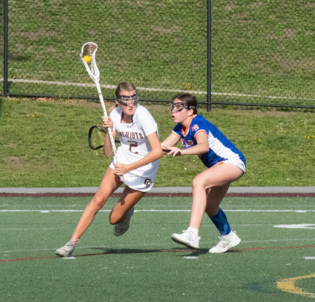 Bridget Fivek fights through defensive pressure en route to scoring one of the Patriots’ 19 goals against Newton South. Photo by Sophie Redmond