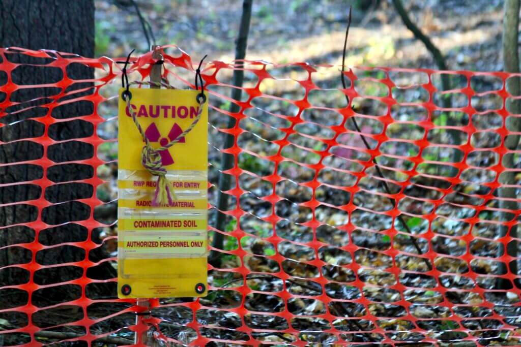 A sign warning about “radioactive material” hangs from temporary fencing near the town’s Powder Mill Woods trail. Photo: Dakota Antelman/The Acton Bridge