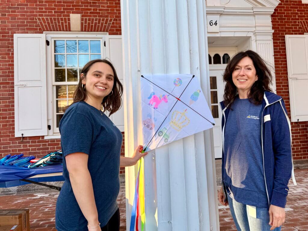 Banker Noelle Bouvier (left) and branch manager Melinda Gladden with a decorated kite outside Middlesex Bank. Photo by Elisabeth Weber