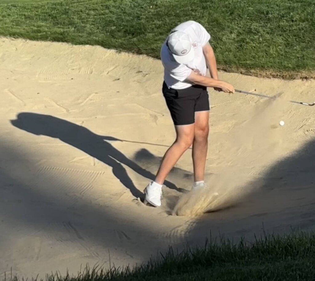 Captain Theo Price blasts his way out of trouble from the bunker on the seventh hole en route to making par. Photo by Carl Sweeney