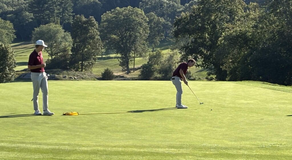 Joe Grasso rolls in a twisting putt on the seventh hole as playing partner Jake Erston looks on. Photo by Carl Sweeney