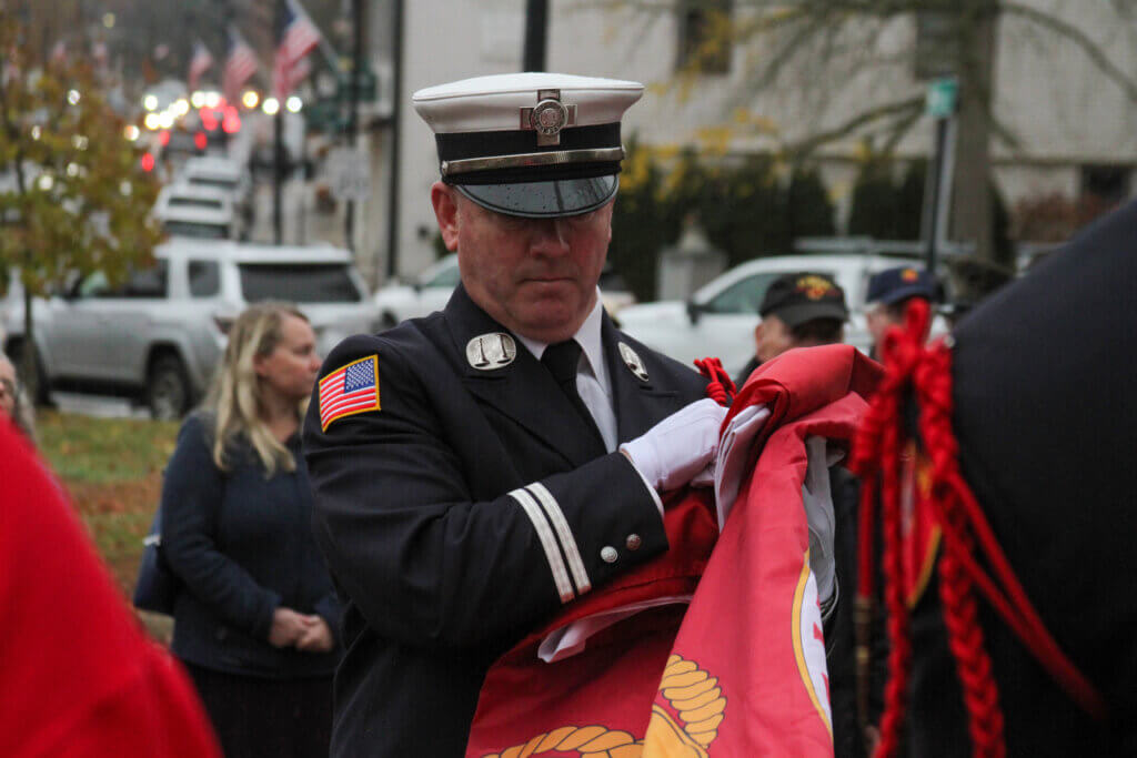 Fire Capt. Sean Murphy, a Marine Corps veteran, prepares a flag to be hoisted in Monument Square. Photo: Dakota Antelman/The Acton Bridge