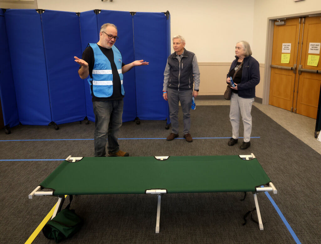 Mike Funaiole, left, Acton Public Health Inspector talks to Donald and Claire Moir after the Acton couple volunteered to serve as shelter-seekers. Photo: Ken McGagh/The Acton Bridge
