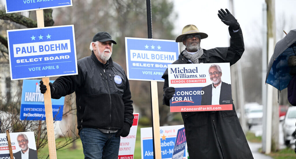 Select Board candidate Paul Boehm, left, and School Committee candidate Michael Williams hold signs outside the Hunt Recreation Center polling place on Tuesday, April 8, 2025. Voters are deciding on two open seats on the Select Board and two open seats on the School Committee. Ken McGagh/The Acton Bridge